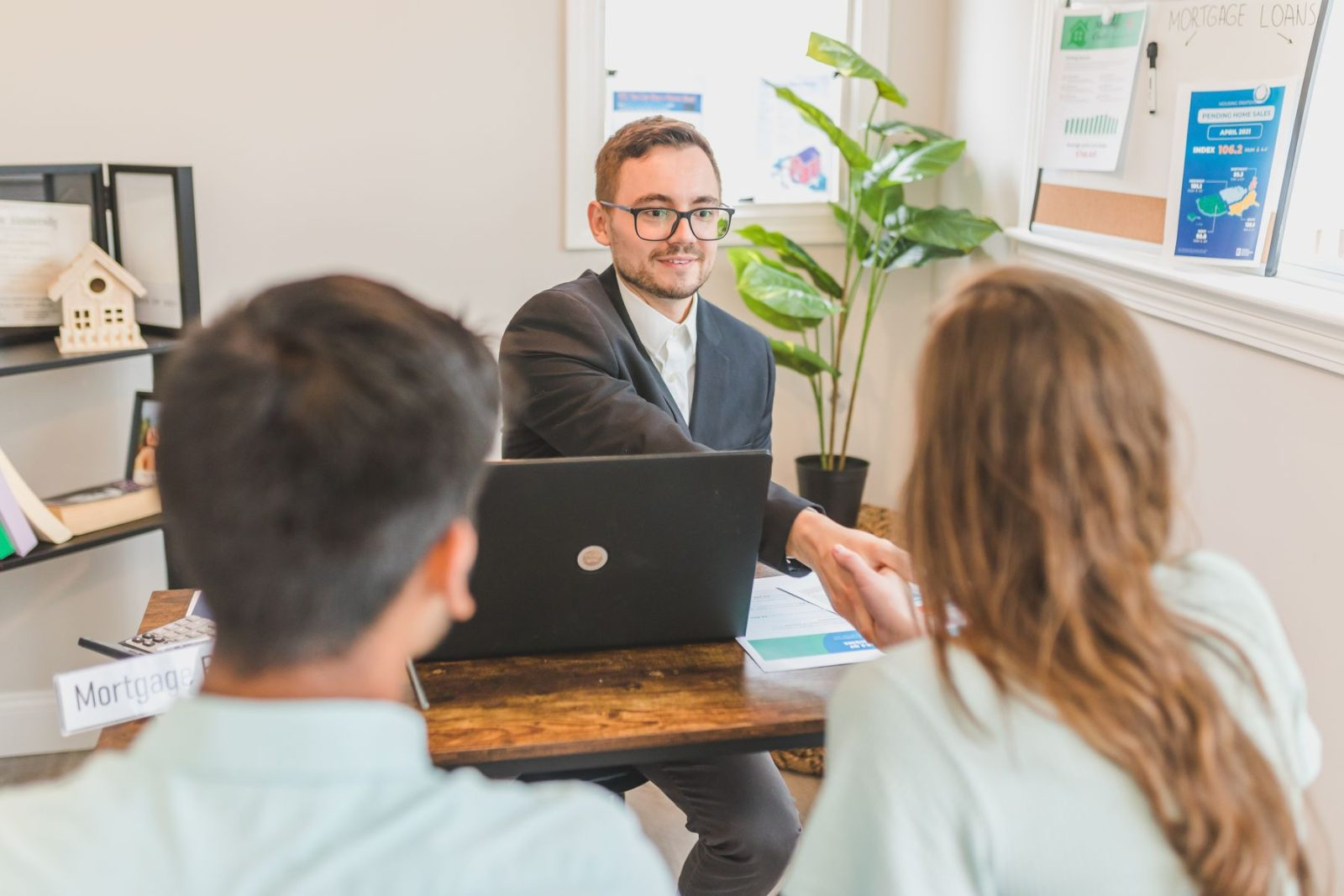 Mortgage loan specialist meeting with two clients at his office desk