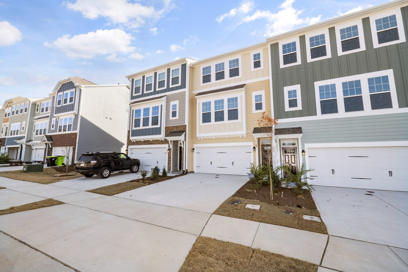 Row of newly built residential townhomes with driveways on a sunny day